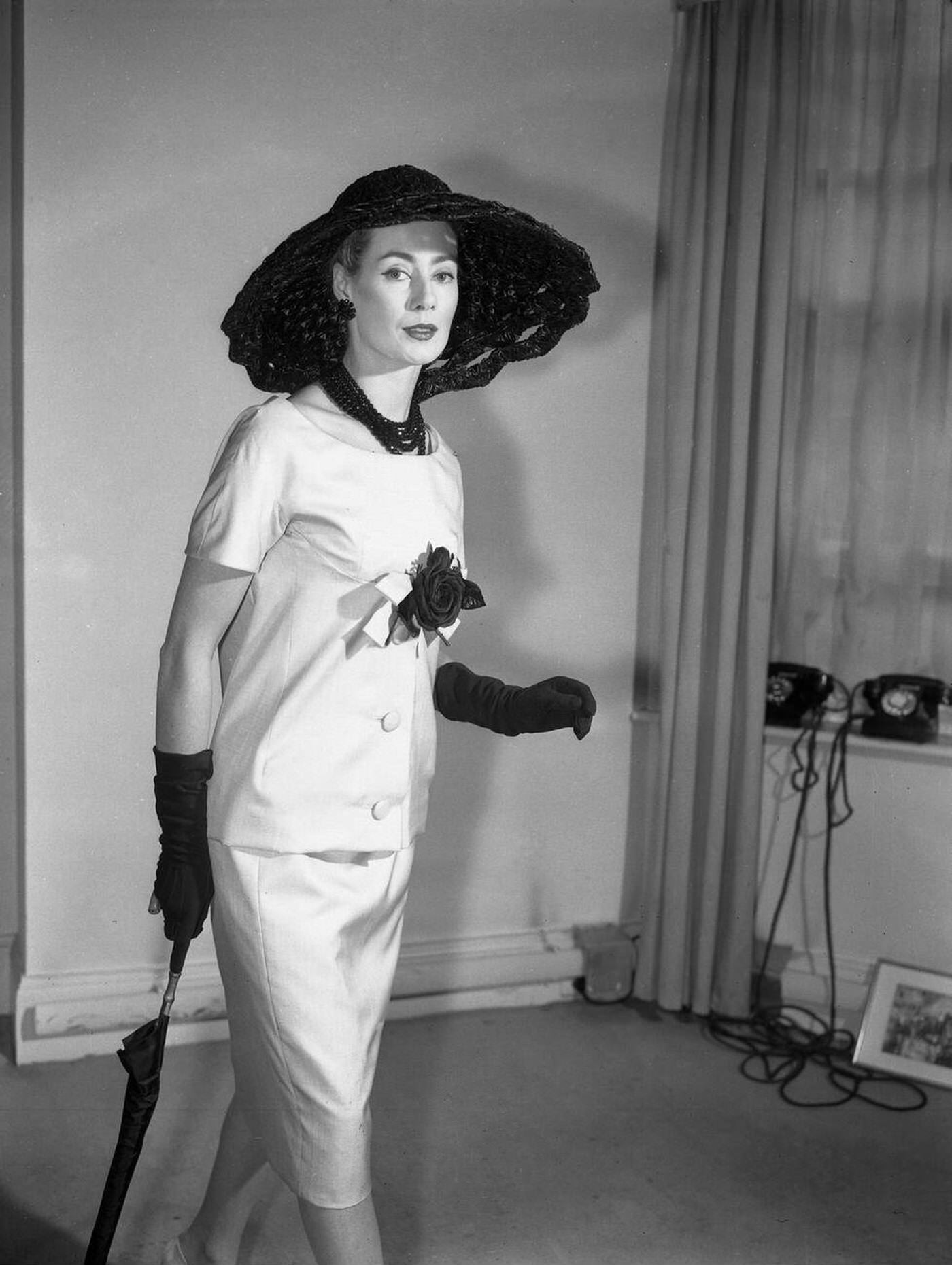 A Beige Silk Afternoon Tunic Dress With A Black Rose Is Worn By Pat O'Reilly During A Showing Of The Christian Dior - London Fashion Collection For Summer, 1959.