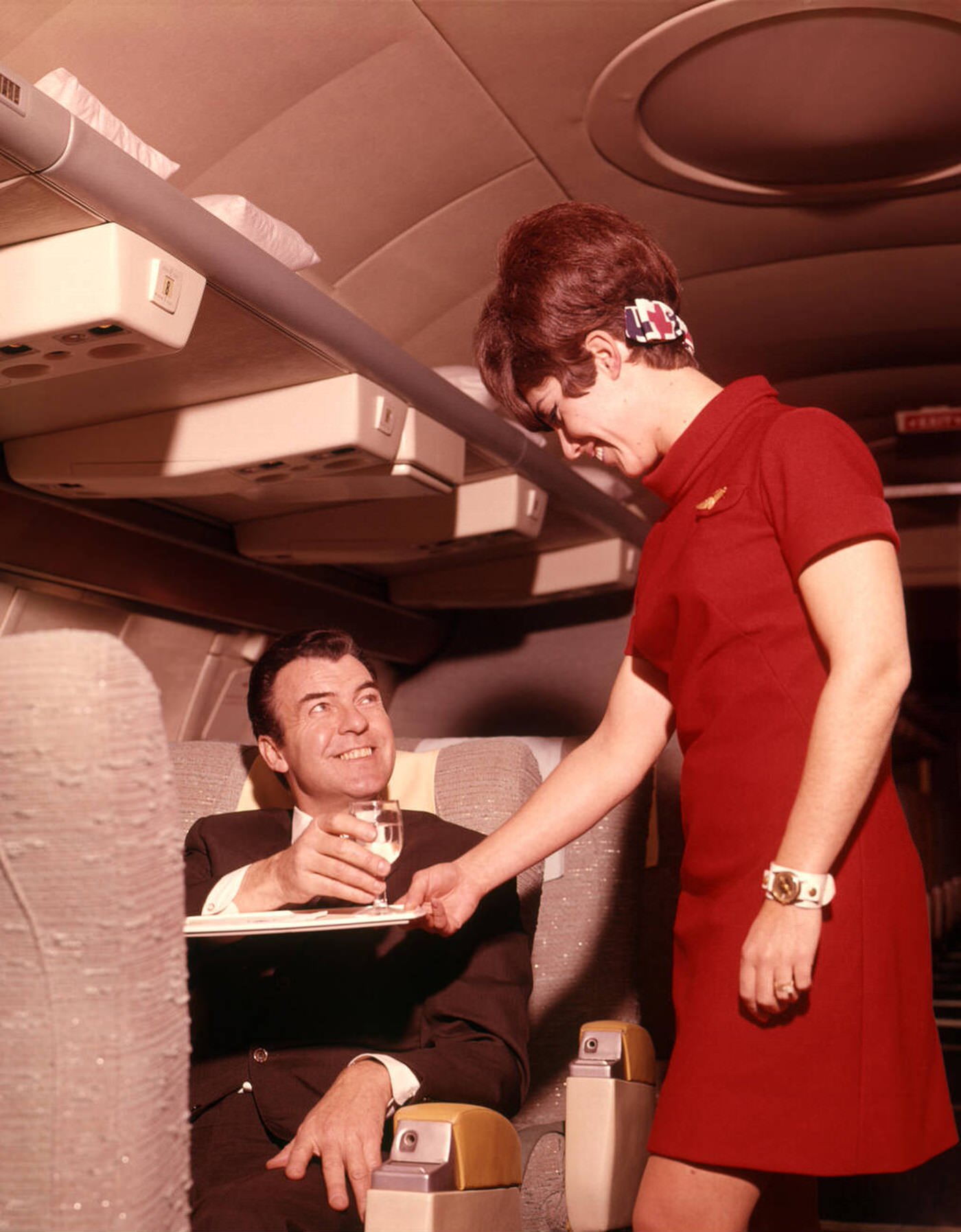 Stewardess Serving A Business Man A Drink On An Airplane, 1960S.
