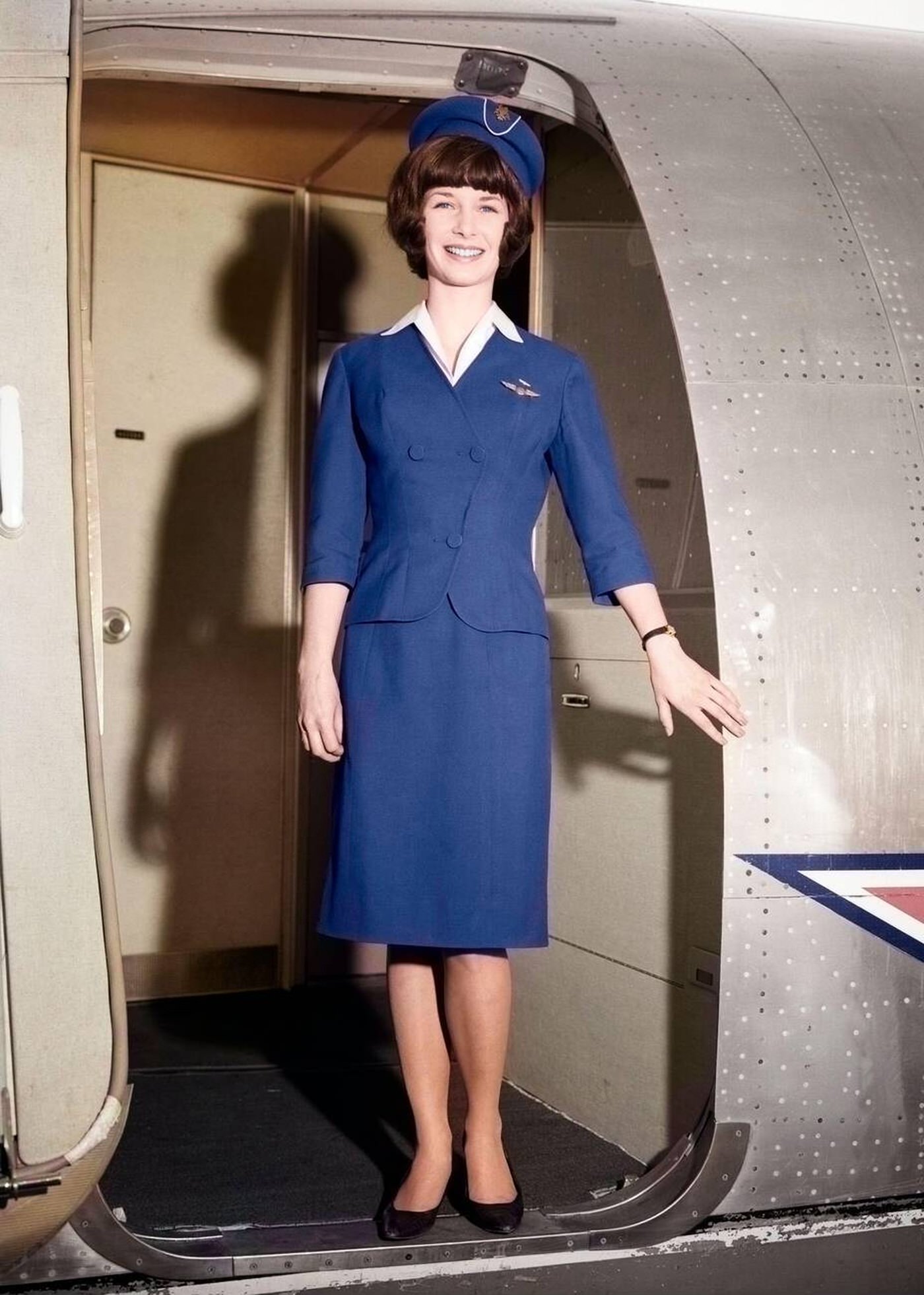 Smiling Stewardess Stands In The Doorway Of An Airplane, 1966.