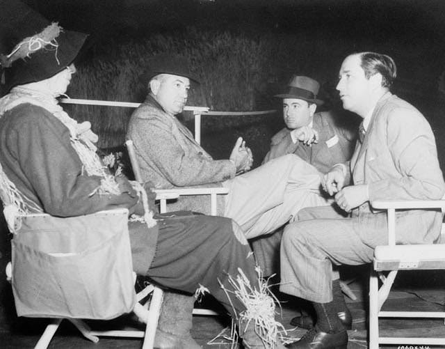 Ray Bolger In Costume As The Scarecrow, Seated With Director Victor Fleming, Choreographer Bobby Connolly And Producer Mervyn Leroy.