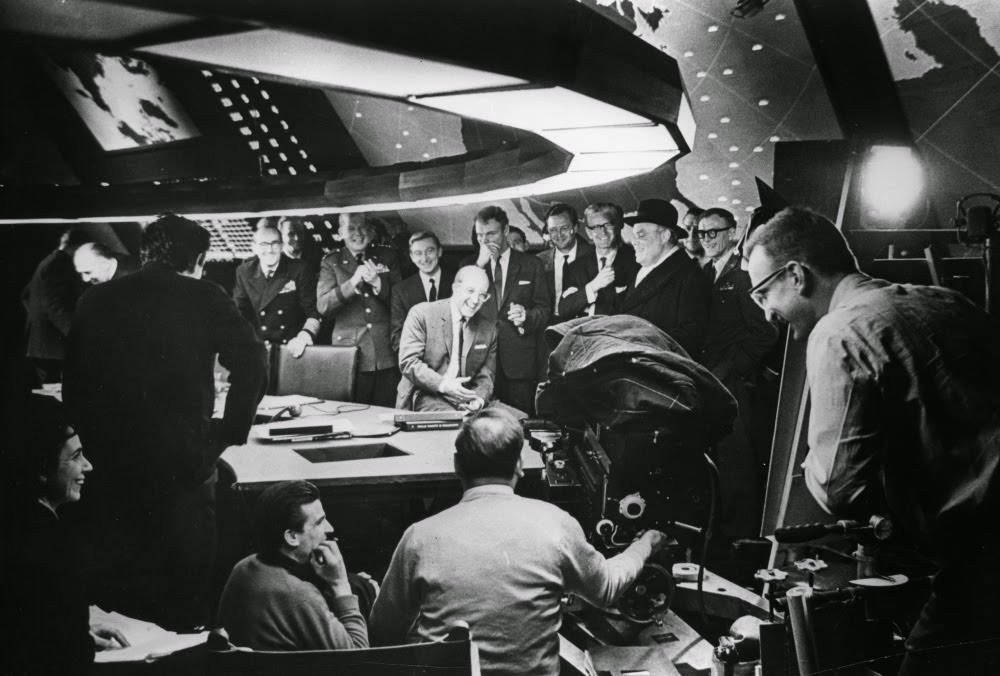 Peter Sellers (Centre) Shares A Joke With Cast And Crew In Ken Adam’s Famous War Room Set.