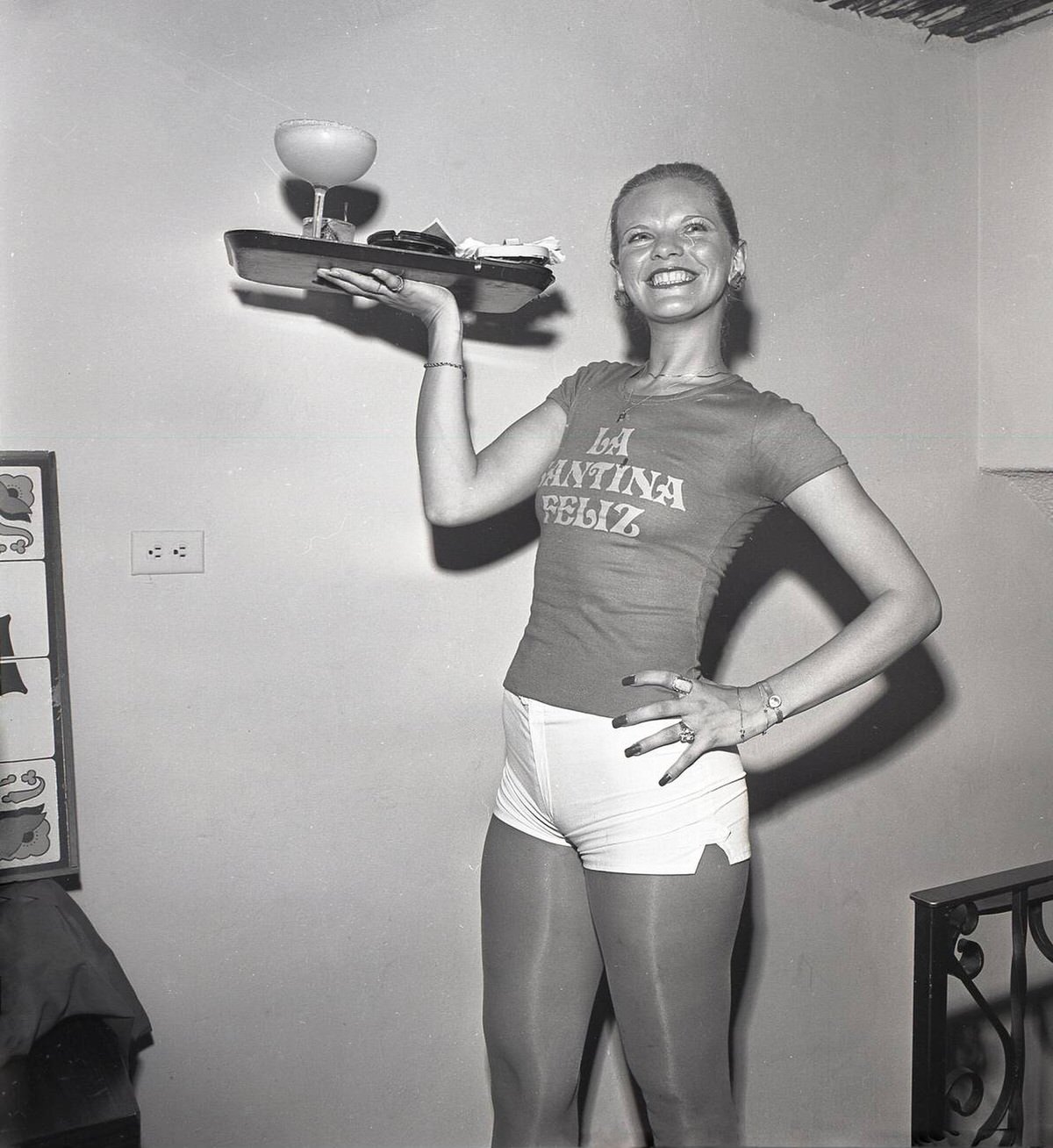 Cocktail Waitress In A T-Shirt And Hotpant Carrying A Tray Of Drinks At La Santina Feliz In Los Angeles, 1960