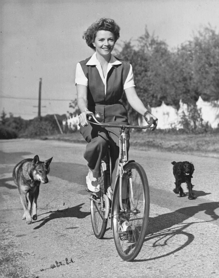Annabella Riding A Bicycle With Her Dogs, 1943.
